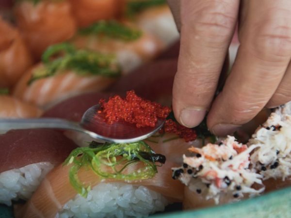 Mão a empratar prato de Sushi